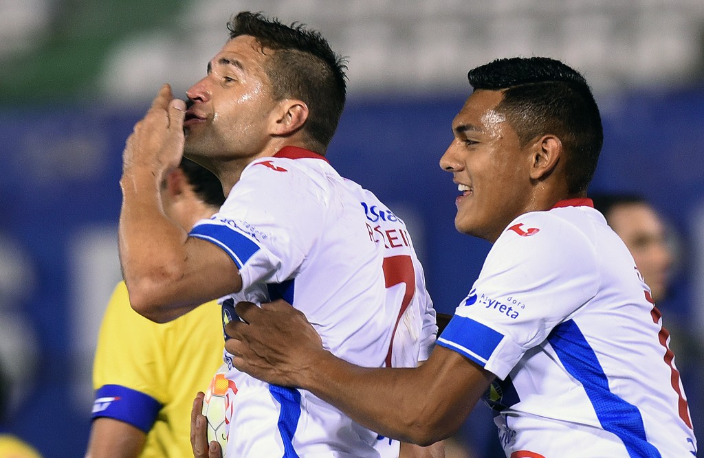 Paraguayan Nacional's footballer Rodrigo Teixeia (L) celebrates after scoring against Chilean Universidad de Concepcion during their Copa Sudamericana football match at Defensores del Chaco Stadium, in Asuncion, Paraguay on August 13, 2015.  AFP PHOTO/ Norberto Duarte