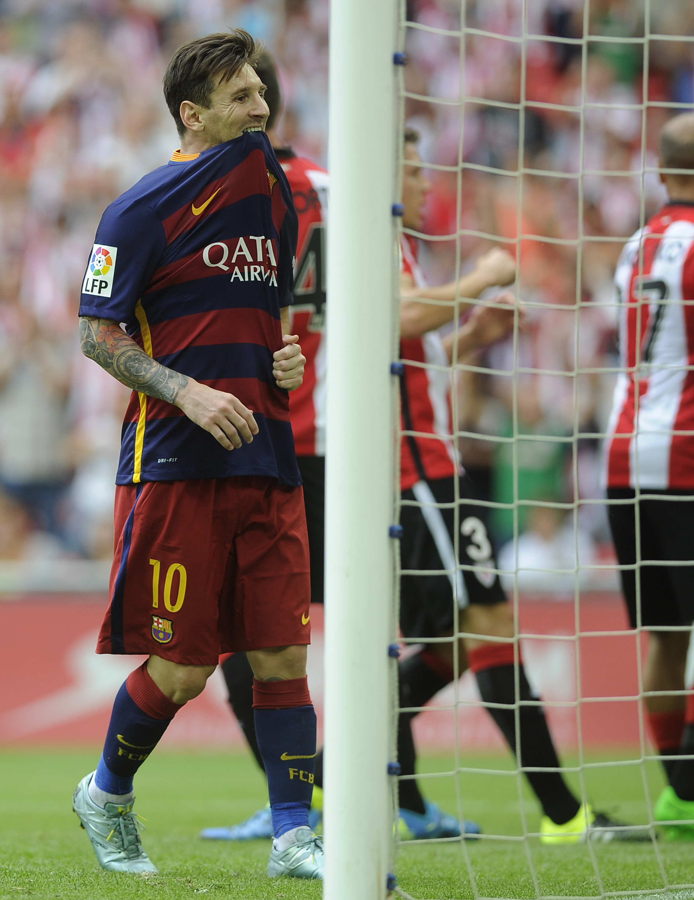 Barcelona's Argentinian forward Lionel Messi (L) bites his jersey during the Spanish league football match Athletic Club Bilbao vs FC Barcelona at the San Mames stadium in Bilbao on August 23, 2015. AFP PHOTO / ANDER GILLENEA