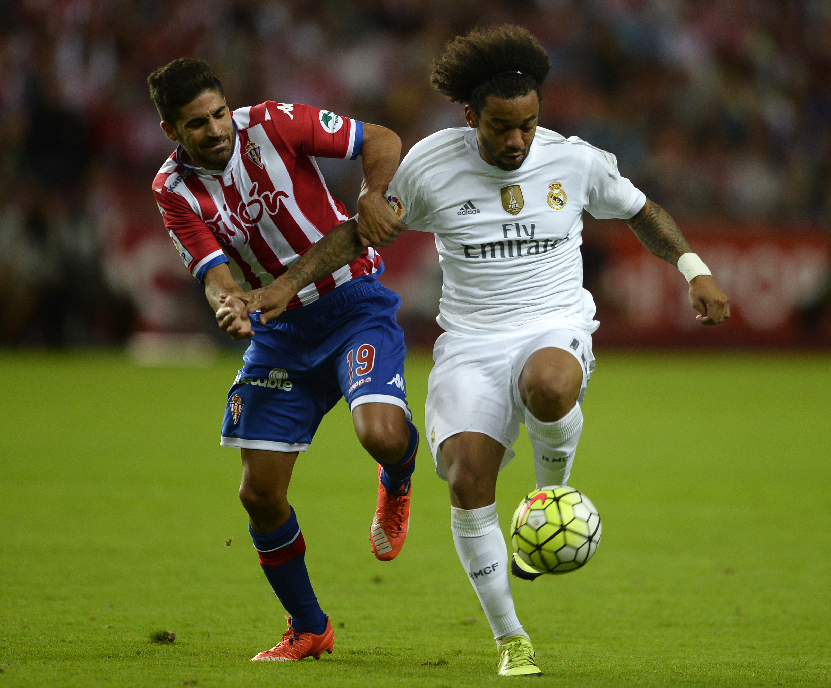 Real Madrid's Brazilian defender Marcelo (R) vies with Sporting Gijon's midfielder Carlos Carmona during the Spanish league football match Sporting Gijon vs Real Madrid CF at the El Molinon stadium in Gijon on August 23, 2015. AFP PHOTO/ MIGUEL RIOPA