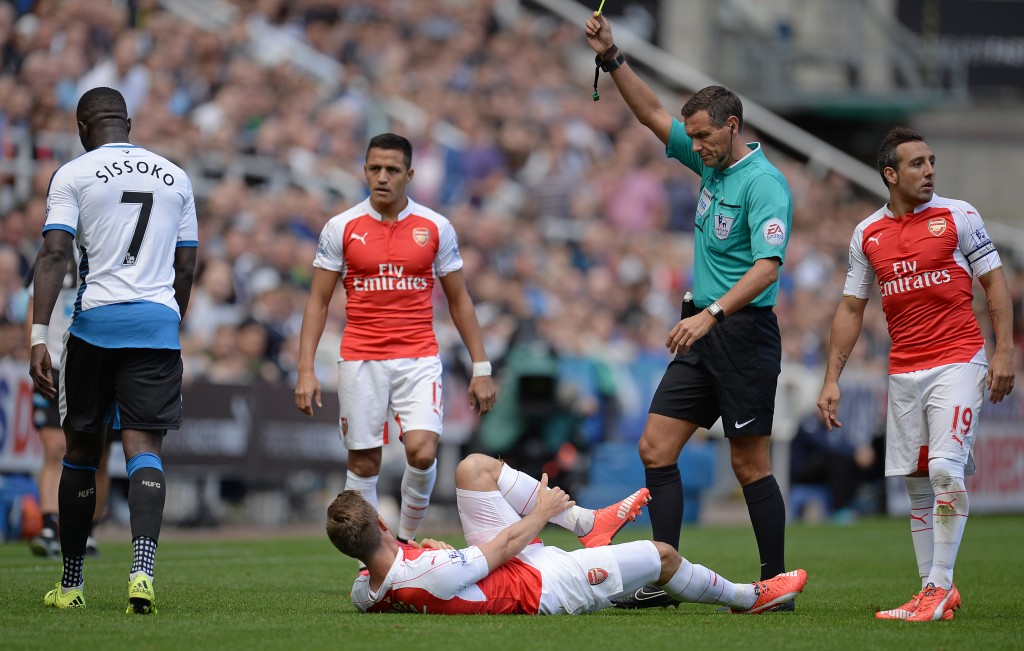 Newcastle United's French midfielder Moussa Sissoko (L) receives a yellow card from referee Andre Marriner after a challenge on Arsenal's Spanish defender Nacho Monreal during the English Premier League football match between Newcastle United and Arsenal at St James' Park in Newcastle-upon-Tyne, north east England, on August 29, 2015. AFP PHOTO / OLI SCARFF RESTRICTED TO EDITORIAL USE. No use with unauthorized audio, video, data, fixture lists, club/league logos or 'live' services. Online in-match use limited to 75 images, no video emulation. No use in betting, games or single club/league/player publications.