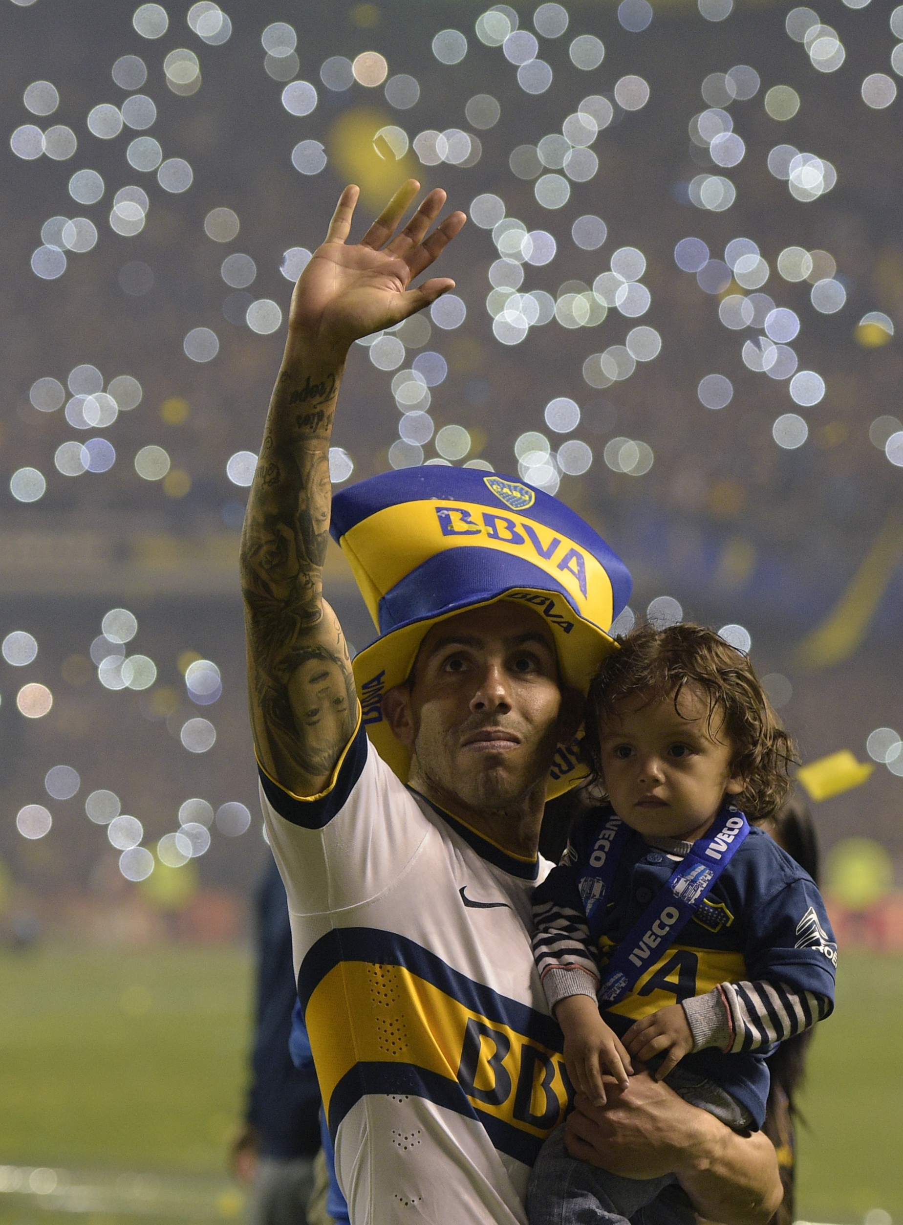 Boca Juniors' forward Carlos Tevez waves to supporters while holding his son after winning Argentina's first division football championship at the "La Bombonera" stadium in Buenos Aires, on November 1, 2015. AFP PHOTO / JUAN MABROMATA