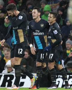 Arsenal's German midfielder Mesut Ozil (C) celebrates with Arsenal's Chilean striker Alexis Sanchez (R) after scoring the opening goal of the English Premier League football match between Norwich City and Arsenal at Carrow Road in Norwich, eastern England on November 29, 2015. AFP PHOTO / LINDSEY PARNABY RESTRICTED TO EDITORIAL USE. No use with unauthorized audio, video, data, fixture lists, club/league logos or 'live' services. Online in-match use limited to 75 images, no video emulation. No use in betting, games or single club/league/player publications. / AFP / LINDSEY PARNABY