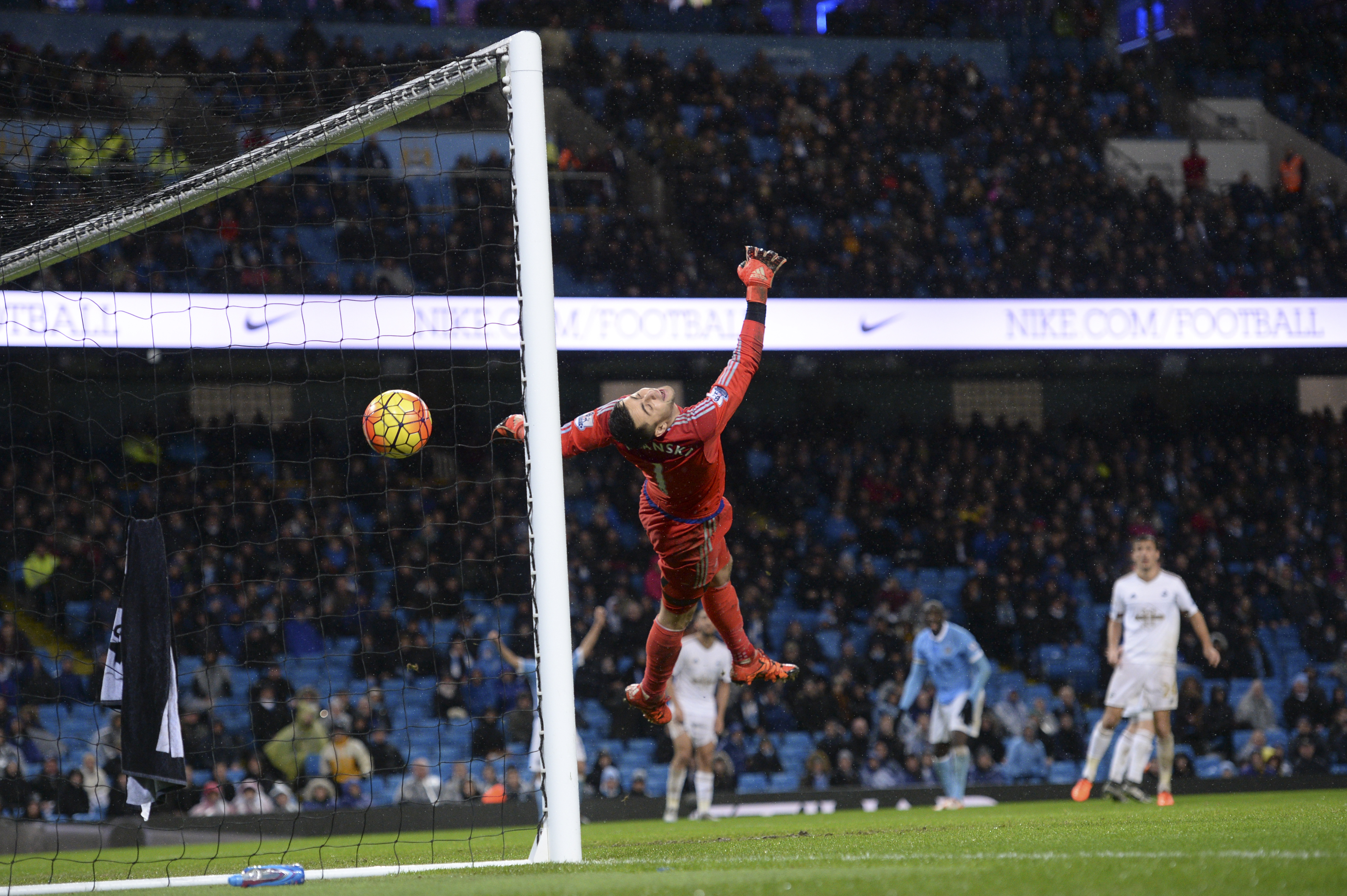 Swansea City's Polish goalkeeper Lukasz Fabianski dives in vain as he fails to stop a deflected shot from Manchester City's Ivorian midfielder and captain Yaya Toure for City's second goal during the English Premier League football match between Manchester City and Swansea City at the Etihad Stadium in Manchester, north west England, on December 12, 2015. AFP PHOTO / OLI SCARFF RESTRICTED TO EDITORIAL USE. No use with unauthorized audio, video, data, fixture lists, club/league logos or 'live' services. Online in-match use limited to 75 images, no video emulation. No use in betting, games or single club/league/player publications. / AFP / OLI SCARFF