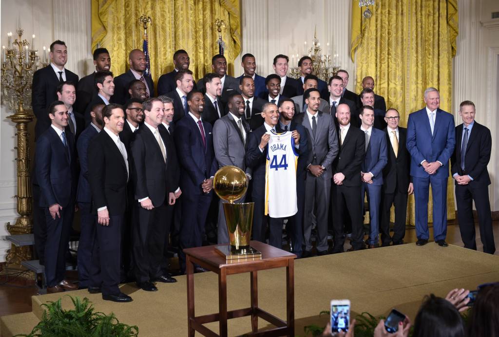 US President Barack Obama holds a jersey as he poses with the 2015 NBA Champion Golden State Warriors during an event in their honor in the East Room of the White House on February 4, 2015 in Washington, DC.. / AFP / MANDEL NGAN