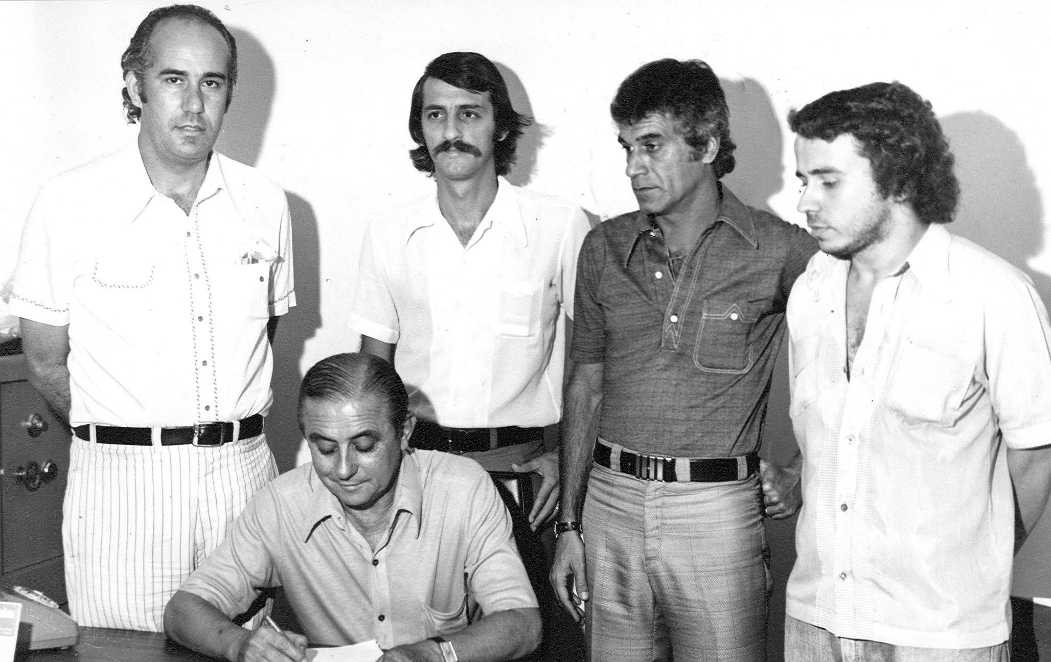 FUTEBOL - URUBATÃO - ESPORTES - ACERVO - Urubatão(o terceiro da esquerda para a direita), técnico do América-SP, Hélcio de Barros(E), Luiz Carlos Giordano(o segundo da esquerda para a direita), o radialista Arlindo Rossi(D) e o presidente Benedito Teixeira(sentado), durante assinatura de contrato com o clube - Estádio Mário Alves de Mendonça - São José do Rio Preto - SP - Brasil - 28/03/1975 - Foto: Acervo/Gazeta Press