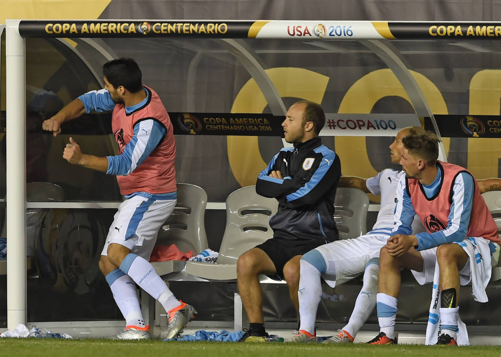Luis Suárez defere socos em vidro no banco de reservas. Uruguaio não entrou em campo em partida que eliminou a seleção de seu país na Copa América (Foto: Don EMMERT/AFP)