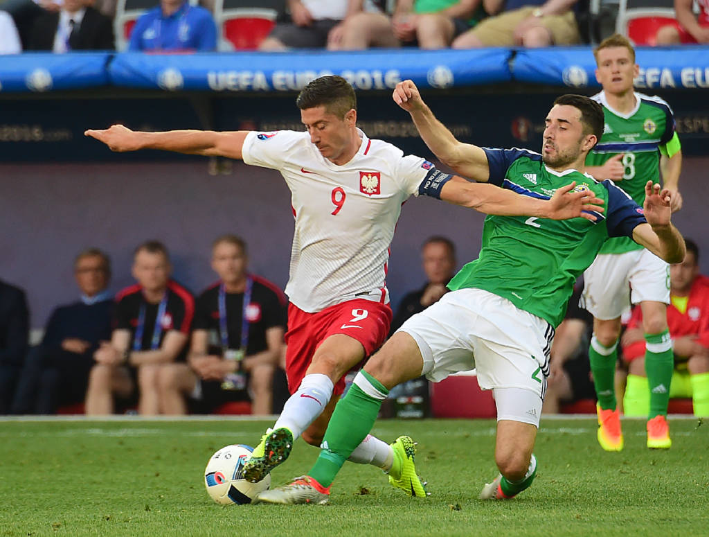 O polonês Robert Lewandowski disputa a bola com Conor McLaughlin, da Irlanda do Norte (Foto: Attila Kisbenedek/AFP)
