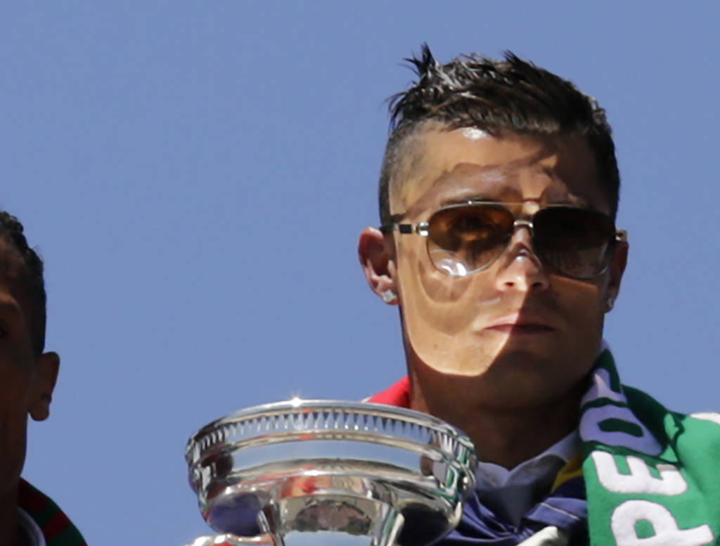 Portugal's forward Cristiano Ronaldo waves to fans holding the trophy on the balcony of the Belem Palace as he celebrates their victory on July 11, 2016 after their Euro 2016 final football win over France yesterday. The Portuguese football team led by Cristiano Ronaldo returned home to a heroes' welcome today after their upset 1-0 win triumph over France in the Euro 2016 final.  / AFP PHOTO / JOSE MANUEL RIBEIRO