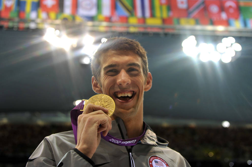 (FILES) This file photo taken on August 03, 2012 in London shows US swimmer Michael Phelps posing on the podium with the gold medal after winning the men's 100m butterfly final swimming event at the London 2012 Olympic Games. The best swimmer in history Michael Phelps finds himself again on the Olympic scene, where he has written the best pages of his career, and soon his legend, with the 2016 Rio Olympic games as his last competition. / AFP PHOTO / CHRISTOPHE SIMON