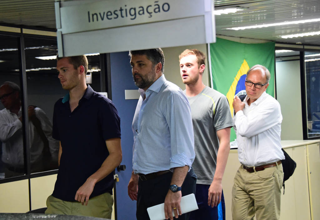 Bentz (de camisa escura) e Conger (cinza) foram tirados do avião, antes de voltar aos Estados Unidos (Foto: Tasso Marcelo/AFP)