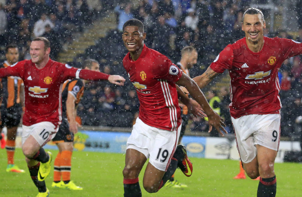 Manchester United's English striker Marcus Rashford (C) celebrates with Manchester United's Swedish striker Zlatan Ibrahimovic (R) and Manchester United's English striker Wayne Rooney (L) after scoring their late winning goal during the English Premier League football match between Hull City and Manchester United at the KCOM Stadium in Kingston upon Hull, north east England on August 27, 2016. Manchester united won the game 1-0. / AFP PHOTO / Lindsey PARNABY / RESTRICTED TO EDITORIAL USE. No use with unauthorized audio, video, data, fixture lists, club/league logos or 'live' services. Online in-match use limited to 75 images, no video emulation. No use in betting, games or single club/league/player publications.  /