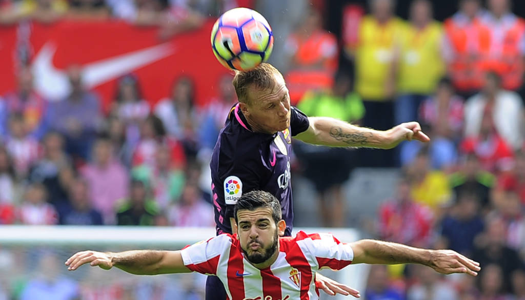Barcelona's French defender Jeremy Mathieu (top) vies with Sporting Gijon's forward Victor during the Spanish league football match Real Sporting de Gijon vs FC Barcelona at El Molinon stadium in Gijon on September 24, 2016. / AFP PHOTO / ANDER GILLENEA