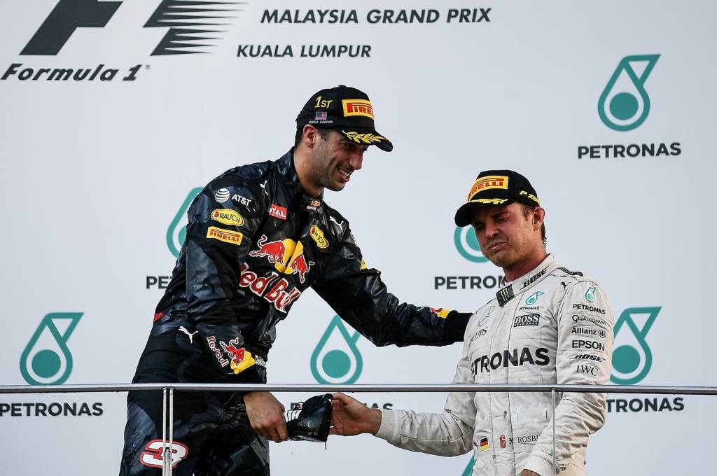 Mercedes AMG Petronas F1 Team's German driver Nico Rosberg (R) reacts after drinking champagne from Red Bull Racing's Australian driver Daniel Ricciardo's shoe on the podium during the Formula One Malaysian Grand Prix in Sepang on October 2, 2016. / AFP PHOTO / MANAN VATSYAYANA