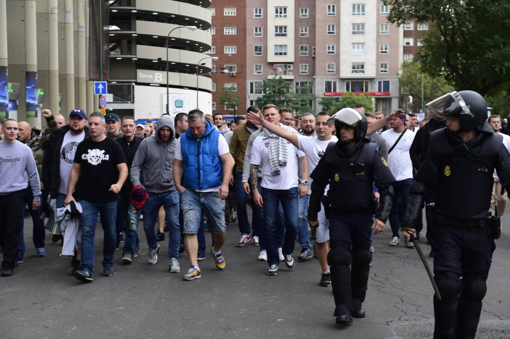 Legia Warsaw football fans are escorted by Spanish poilce into the stadium to take their seats ahead of the UEFA Champions League football match Real Madrid CF vs Legia Legia Warszawa at the Santiago Bernabeu stadium in Madrid on October 18, 2016. Three Polish football fans were arrested today after they attacked waitresses in a bar in the La Latina district of Madrid, stealing the mobile phone of one woman and attempting to rob cash from the till, a police spokesperson confirmed to AFP. / AFP PHOTO / PIERRE-PHILIPPE MARCOU