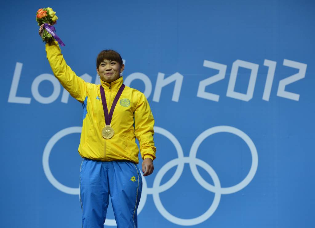 (FILES) This file photo taken on July 31, 2012 shows Kazakhstan's Maiya Maneza posing on the podium after receiving her gold medal for the women's 63kg group A weightlifting event, at The Excel Centre in London on July 31, 2012 during the London 2012 Olympic Games.  The International Olympic Committee on October 27, 2016 stripped three Kazakh weightlifters of gold medals won at the London 2012 Games for doping. Zulfiya Chinshanlo, Maiya Maneza and Svetlana Podobedova were all caught in new testing of hundreds of samples from the London and 2008 Beijing Olympics.  / AFP PHOTO / YURI CORTEZ