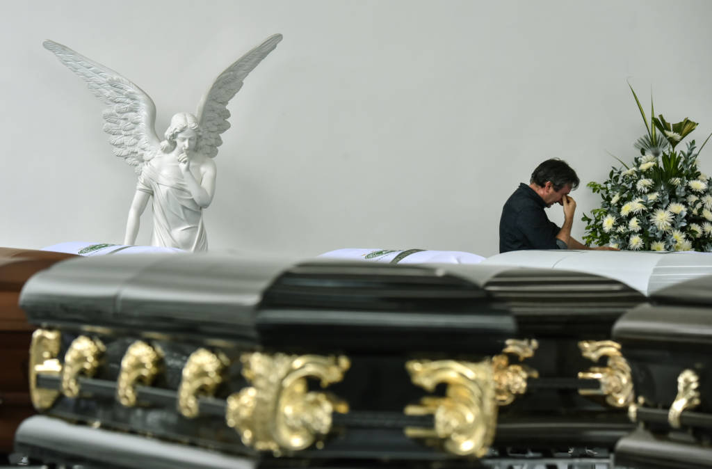Roberto D'Machi, a relative of Nilson Junior Folle, one of the players of Brazilian football team Chapecoense Real killed in a plane crash in the Colombian mountains, mourns next to his coffin at the San Vicente mortuary in Medellin on December 1, 2016. The pilot of a charter plane carrying the Brazilian football team Chapecoense Real radioed frantically that he was out of fuel minutes before slamming into a hillside near Medellin with 77 people on board, an audio recording showed. / AFP PHOTO / Luis ACOSTA