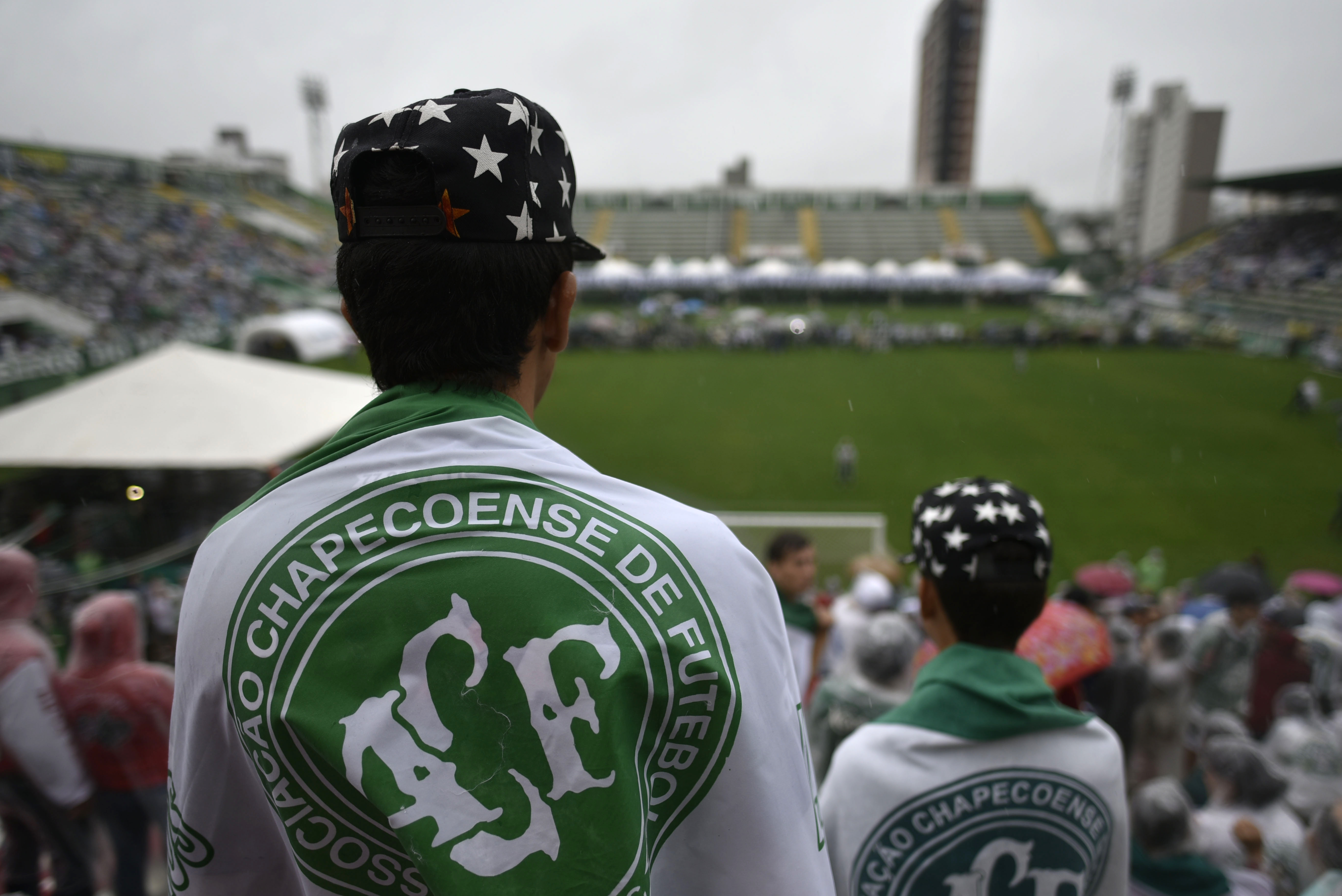 People await for the arrival of the funeral cortege of the players of Brazilian football team Chapecoense Real killed in a plane crash in the Colombian mountains, at the Arena Conda stadium in Chapeco, in the southern Brazilian state of Santa Catarina, on December 3, 2016. The first of two Brazilian air force planes carrying the remains of a football team killed in a plane crash arrived Saturday in the city of Chapeco in southern Brazil. / AFP PHOTO / DOUGLAS MAGNO