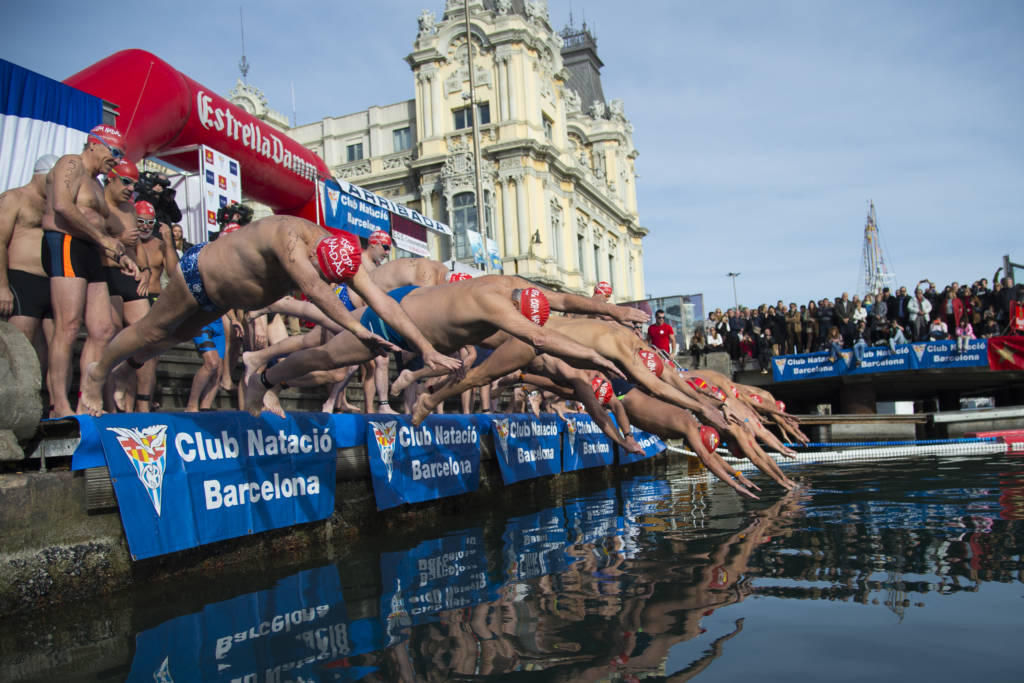 Participants jump into the water during the 107th edition of the Copa Nadal (Christmas Cup) in Barcelona's Port Vell on December 25, 2016.   The traditional 200-meter Christmas swimming race gathered more than 300 participants on Barcelona's old harbour.  / AFP PHOTO / JOSEP LAGO