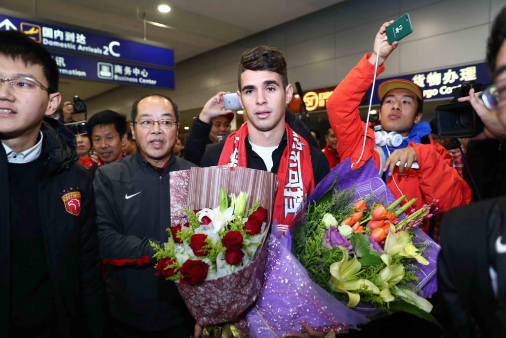 Brazilian football player Oscar (C) is escorted as he arrives at Shanghai airport on January 2, 2017. Brazilian midfielder Oscar landed in Shanghai on January 2, 2017 where the 25-year-old was set to smash the Asian transfer record with a reported 63 million USD deal with Shanghai SIPG. / AFP PHOTO / STR / China OUT