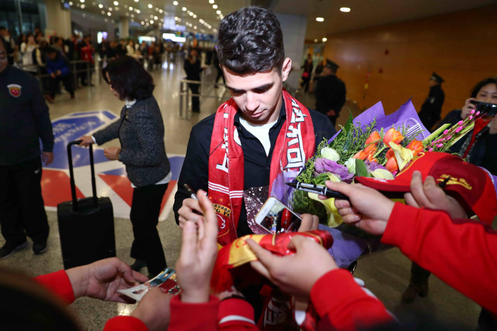 Brazilian football player Oscar (C) signs autographs for Shanghai SIPG fans as he arrives at Shanghai airport on January 2, 2017. Brazilian midfielder Oscar landed in Shanghai on January 2, 2017 where the 25-year-old was set to smash the Asian transfer record with a reported 63 million USD deal with Shanghai SIPG. / AFP PHOTO / STR / China OUT
