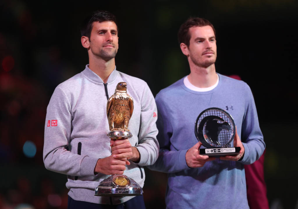 Serbia's Novak Djokovic (L) poses with the winner's trophy after beating Britain's Andy Murray during their final tennis match at the ATP Qatar Open in Doha on January 7, 2017. / AFP PHOTO / KARIM JAAFAR