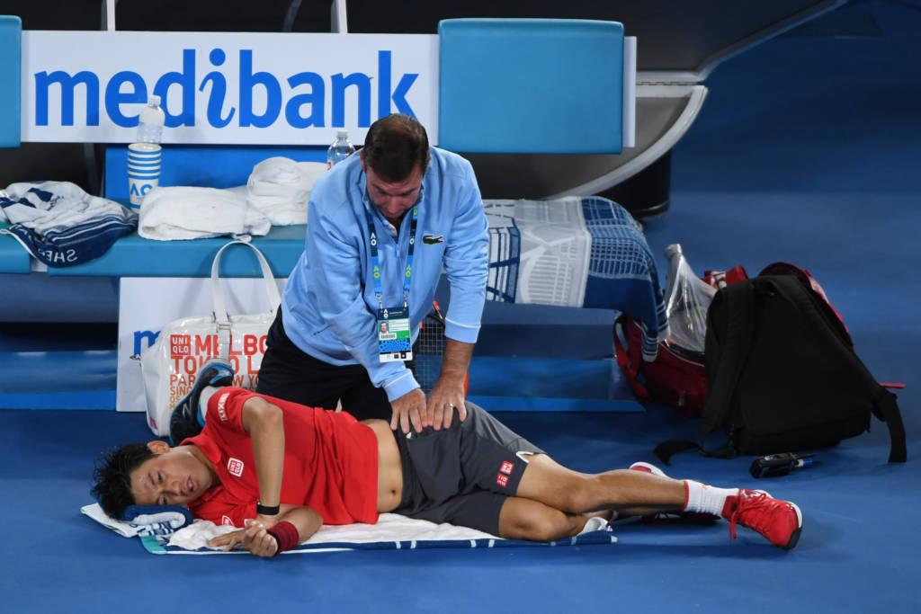 Japan's Kei Nishikori receives physio while playing against Switzerland's Roger Federer during their men's singles fourth round match on day seven of the Australian Open tennis tournament in Melbourne on January 22, 2017. / AFP PHOTO / WILLIAM WEST / IMAGE RESTRICTED TO EDITORIAL USE - STRICTLY NO COMMERCIAL USE