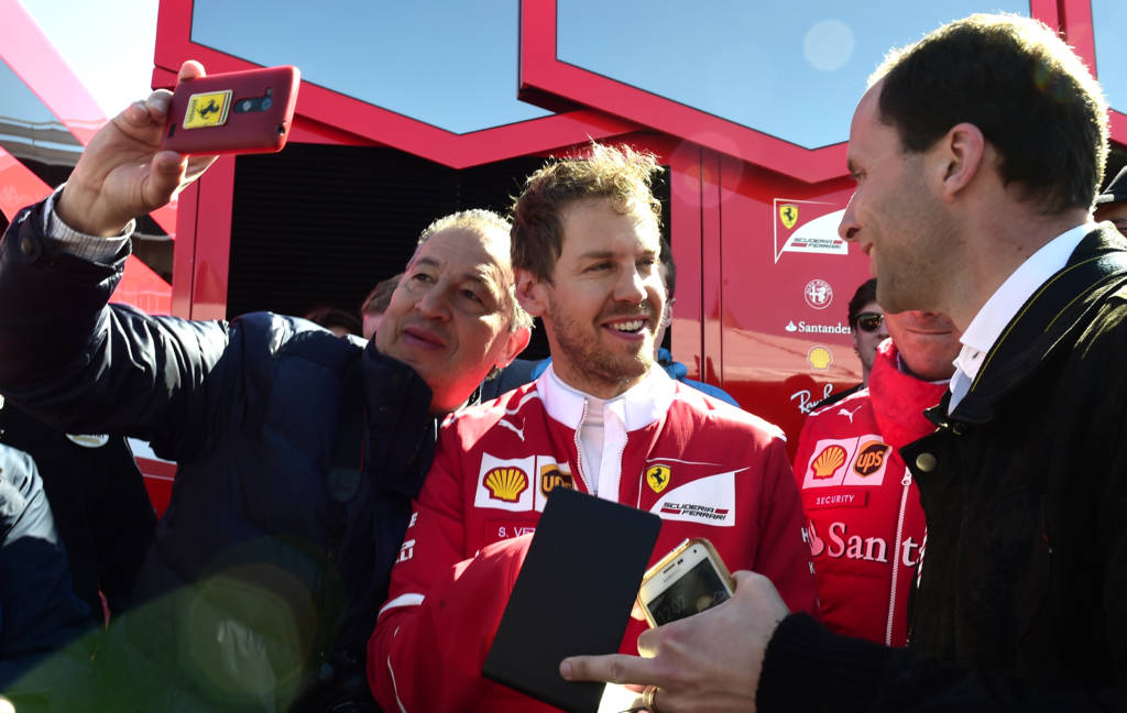 Ferrari's German driver Sebastian Vettel (L) signs autographs at the Circuit de Catalunya on March 1, 2017 in Montmelo on the outskirts of Barcelona during the third day of the first week of tests for the Formula One Grand Prix season.  / AFP PHOTO / JOSE JORDAN